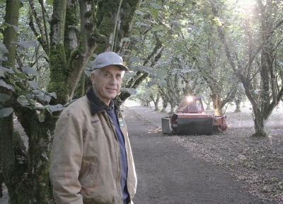 Farmer Bruce Chapin standing in front of a sweeper preparing to harvest hazelnuts at his orchard near Salem, Ore. 