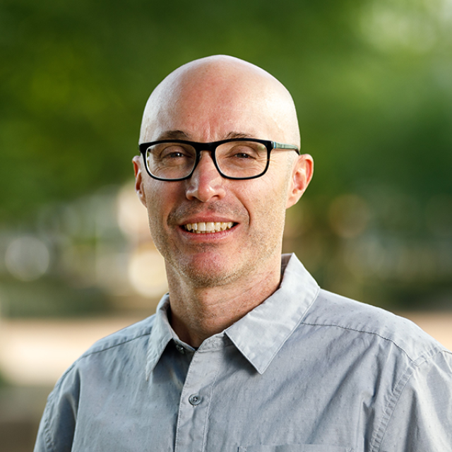 Dr. John McCutcheon with a blurred green background